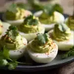 Creamy Avocado Deviled Eggs garnished with herbs