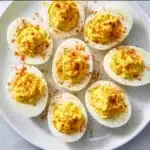 Classic deviled eggs garnished with paprika on a platter