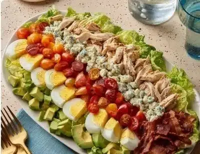 Delicious Cobb Salad with greens, chicken, bacon, egg, and avocado on a plate.